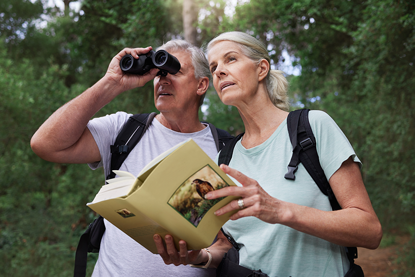 Senior caucasian couple using binoculars and a book