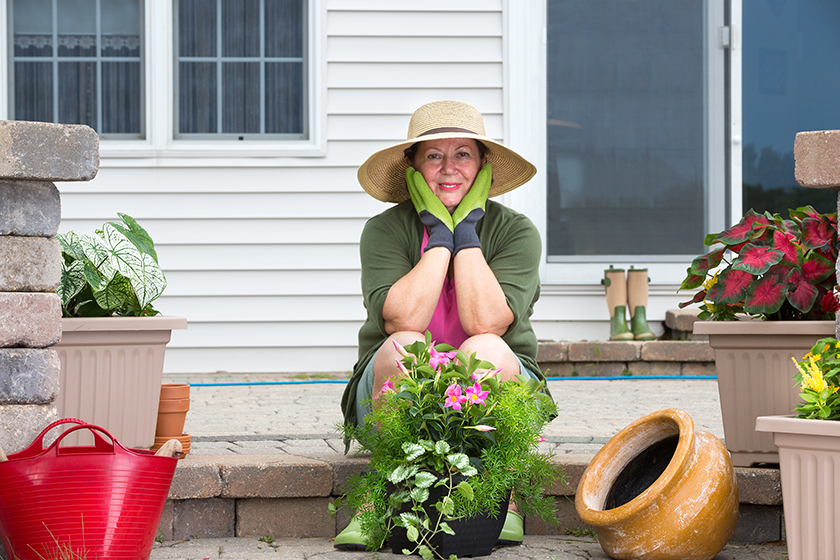 Elderly woman pausing while potting up plants